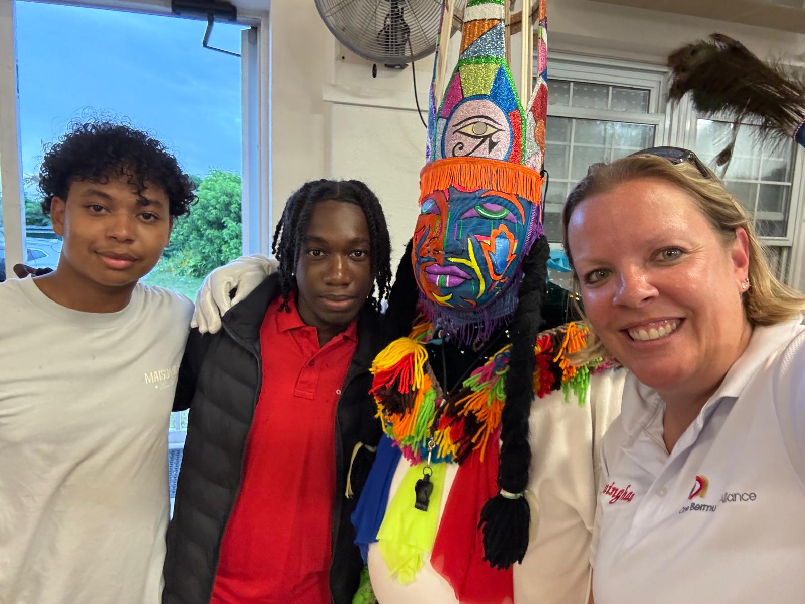 Victoria with two young men beside a Gombey costume